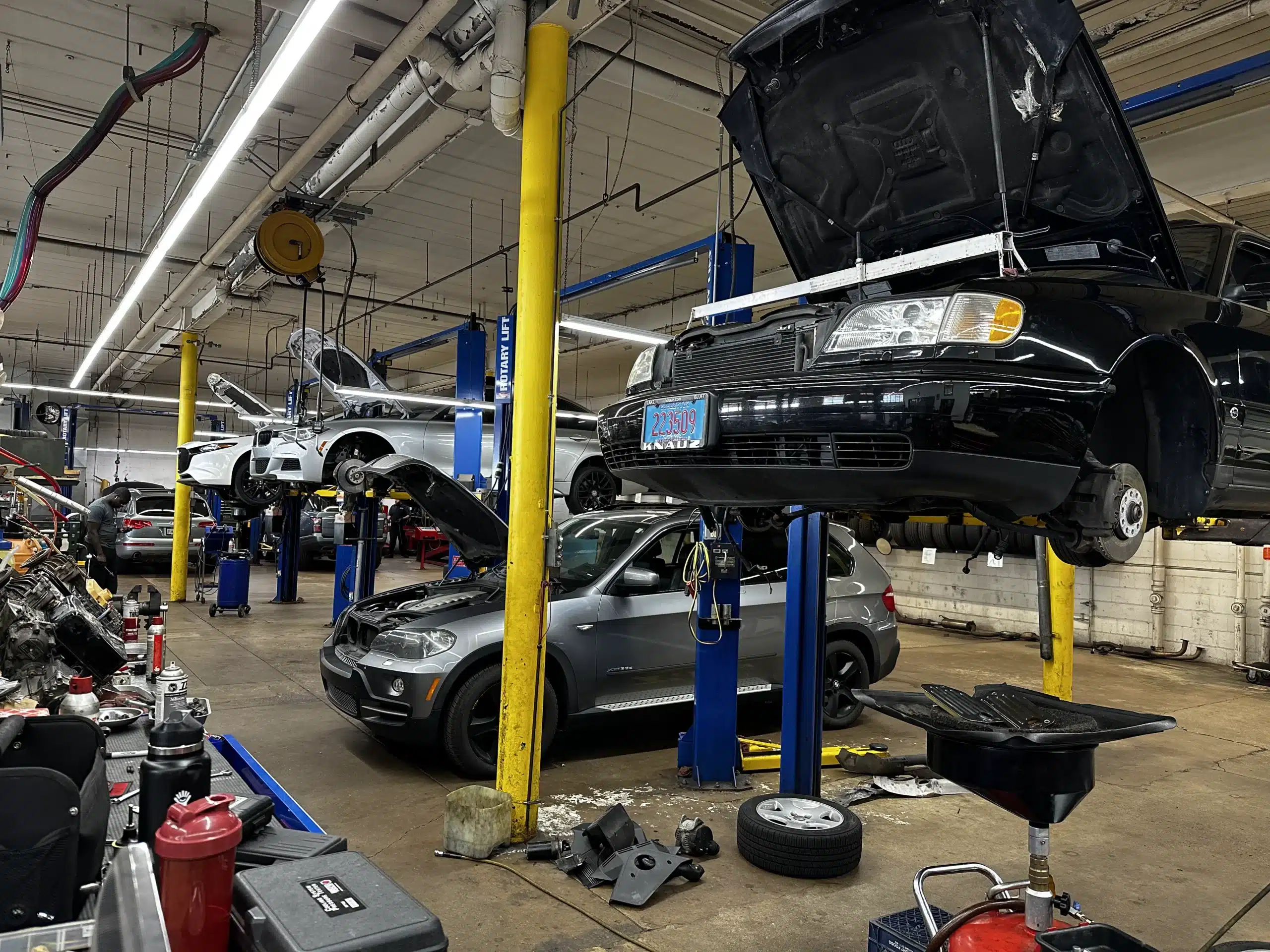 European Vehicle Maintenance in Milwaukee, WI by O’Reilly Motor Cars, Inc. The image shows several cars lifted on hydraulic lifts with their hoods open, highlighting the professional and comprehensive services provided by the shop.