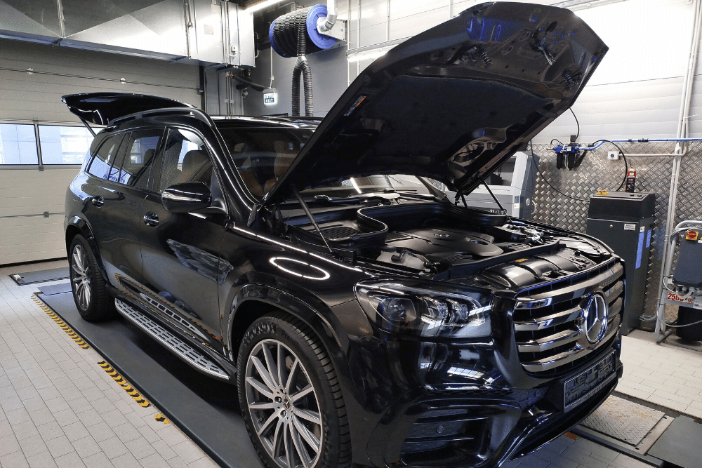 Mercedes Maintenance in Milwaukee, WI at O'Reilly Motor Cars. A black Mercedes-Benz SUV with its hood open sits inside an automotive service bay for inspection or repair.