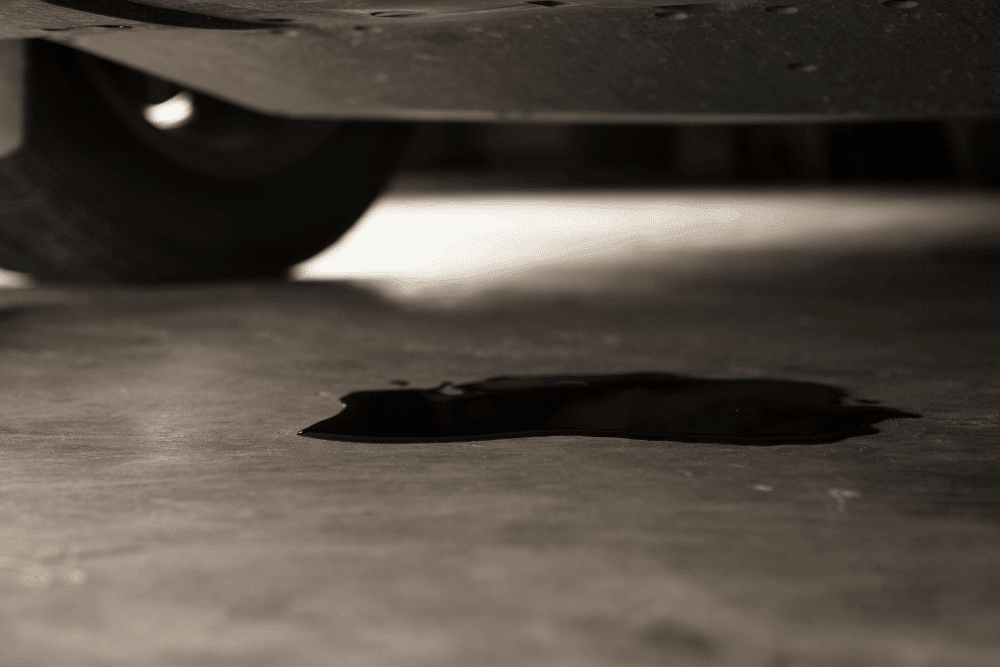 Oil leak, auto repair in Milwaukee, WI, at O'Reilly Motor Cars. Image of engine oil leaking onto the ground beneath a vehicle, highlighting professional diagnostics and repairs that help prevent engine damage and keep your vehicle operating safely and reliably.
