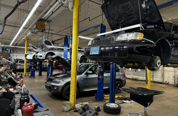 European Vehicle Maintenance in Milwaukee, WI by O’Reilly Motor Cars, Inc. The image shows several cars lifted on hydraulic lifts with their hoods open, highlighting the professional and comprehensive services provided by the shop.