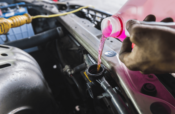 fluid checks, auto repair in Milwaukee, WI at O'Reilly Motor Cars. A person pouring coolant into a car’s reservoir.